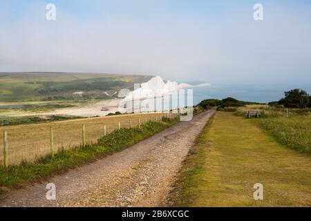 Panoramablick auf einen Pfad, der tagsüber zu den Seven Sisters Chalk Cliffs an der Küste von Sussex in Südengland führt Stockfoto