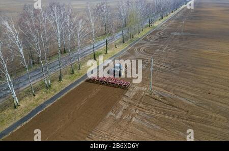 Antenne Blick von oben auf einen Traktor, Mähdrescher pflügen landwirtschaftliche Flächen im Frühjahr Stockfoto