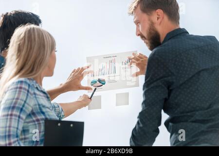 Junge Mitarbeiter zeigen auf Finanzgrafik Stockfoto