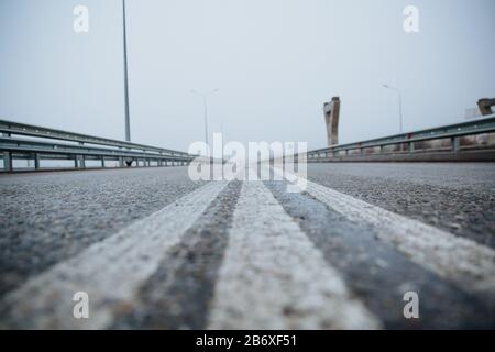 Die Trennlinie auf der Straße ist weiß, die Ansicht von unten auf der Straße, die asphaltiert ist. Straßenmarkierungen auf Asphalt auf der Straße. Stockfoto