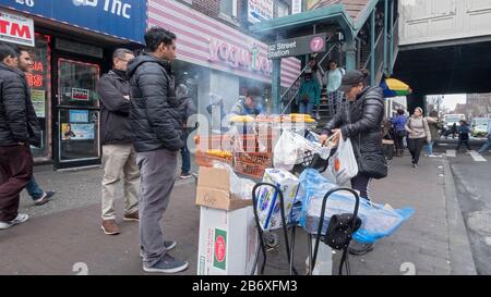 Zwei südamerikanische Frauen verkaufen Mais und Huhn von einem Stand an der 82nd Street in Jackson Heights, Queens, New York City. Stockfoto