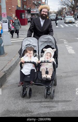 Ein Rabbi aus Satmar und seine 2 Töchter in einem Kinderwagen, der auf der Lee ave. In der Williamsburg Secrion von Brooklyn, New York, läuft. Stockfoto