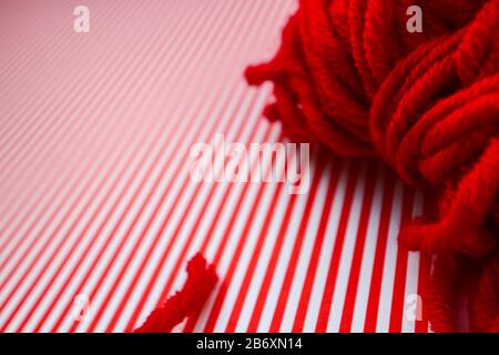 Roter Garnball auf rot gestreiftem Hintergrund. Stockfoto