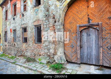 Altes Haus mit großem Holztor und zerbrochener Mauer Stockfoto