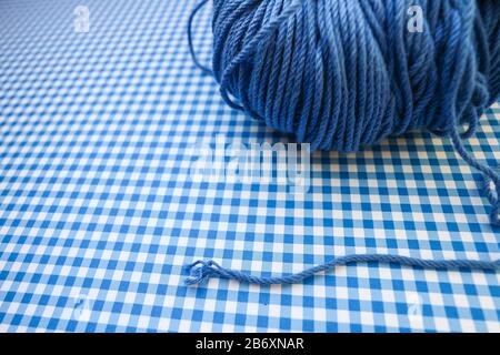 Blauer Garnball auf blauem kariertem Hintergrund. Stockfoto