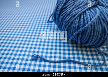Blauer Garnball auf blauem kariertem Hintergrund. Stockfoto