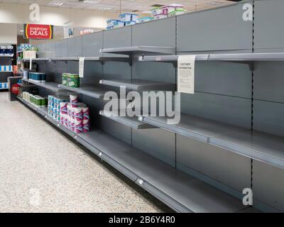 Leere Regale in einem Supermarkt, in dem normalerweise Gewebe wc und Küchenrollen enthalten sind, die von Leuten geräumt wurden, die von Versorgungsschwierigkeiten aufgrund von Kovid -19 betroffen waren Stockfoto