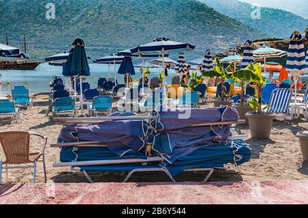 Bali, Crete, Griechenland - 10.15.2019: Das Ende der Schwimmsaison. Sonnenliegen und Sonnenschirme werden am Strand gesammelt Stockfoto