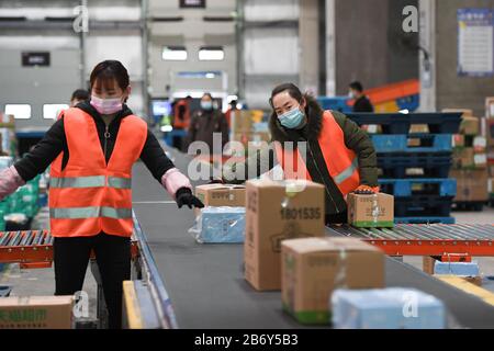 Peking, China. März 2020. Arbeiter packen Waren in einem Logistikzentrum in Peking, der Hauptstadt Chinas, am 12. März 2020. Das Logistikzentrum bearbeitet täglich rund 50.000 Bestellungen, während es den Betrieb unter epidemischen Vorbeugungs- und Kontrollmaßnahmen wieder aufnimmt. Credit: Ju Huanzong/Xinhua/Alamy Live News Stockfoto