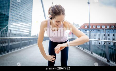 Die Sportlichkeit der Frau hat nach dem Training ihre Smartwatch hinter sich. Weibliche Läuferin macht sich beim Joggen eine Pause. Stockfoto