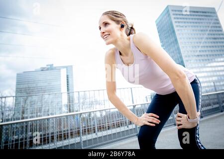 Die Sportlichkeit der Frau hat nach dem Training ihren Atem. Weibliche Läuferin macht sich beim Joggen eine Pause. Frau Athletin erholte sich nach dem Workout Stockfoto