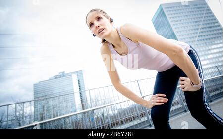Die Sportlichkeit der Frau hat nach dem Training ihren Atem. Weibliche Läuferin macht sich beim Joggen eine Pause. Frau Athletin erholte sich nach dem Workout Stockfoto