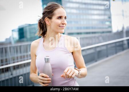 Junge Athletin nach dem Joggen mit Wasserflasche in der Hand.junge Sportfrau nach Joggen mit Wasserflasche in der Hand. Stockfoto