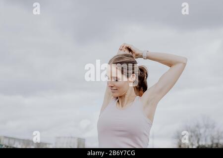 Junge Sportlerin macht Dehnungen nach dem Sport in der Stadt. Junge Sportlerin macht nach dem Sport in der Stadt Dehnübungen. Stockfoto