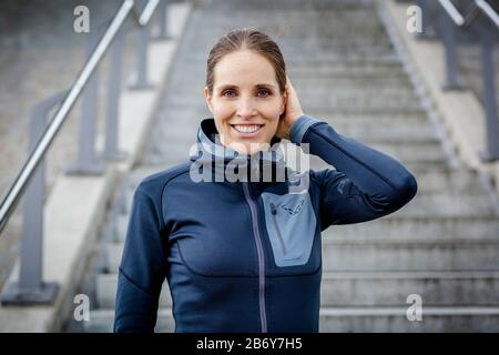 Sportliche junge Frauen mit Sportbekleidung stehen vor der Treppe. Junge Frau mit Sportbekleidungstief vor einer Treppe. Stockfoto