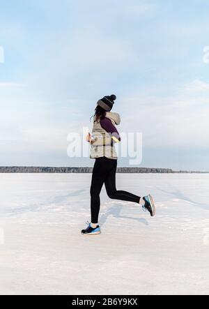 Frau Läuferin, die im Winter-Trail-Marathon auf dem Schneefeld läuft Stockfoto