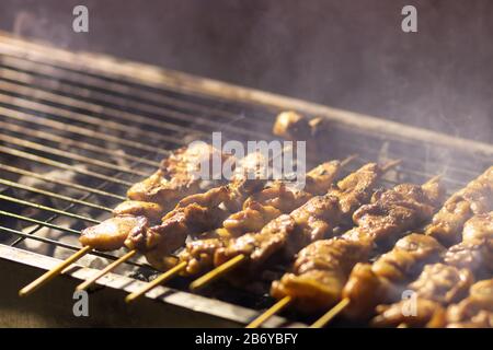 Hühnerbrocken Spieße, Grill, Grill. Auf einem Grillplatz aus Metall. In den Grillphasen. Dunkler Nachthintergrund, koscheres Essen. Viel Rauch Stockfoto