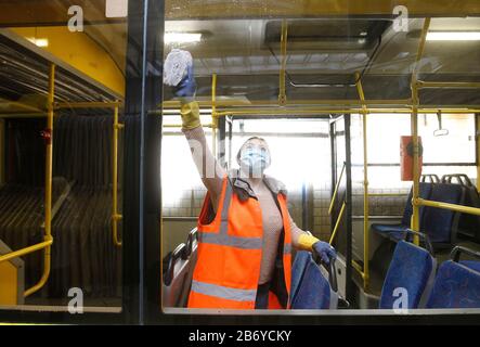 Ein Arbeiter, der eine Schutzmaske trägt, desinfiziert einen Personenkraftwagenbus als präventive Maßnahme gegen das COVID-19-Coronavirus in einem Trolleybusdepot.Vom 12. März bis 3. April 2020 führt die Ukraine eine dreiwöchige Quarantäne ein, um dem neuen Coronavirus COVID-19 wegen der weltweiten "ovid-19-Coronavirus-Epidemie" entgegenzuwirken. Die Quarantäne in der Ukraine sieht die Schließung von Bildungseinrichtungen, das Verbot von Massenversammlungen von mehr als 200 Personen, die Schließung von Luftdiensten mit einigen Ländern vor. Die Weltgesundheitsorganisation erklärte das Coronavirus am 11. März 2020 zu einer globalen Pandemie. Stockfoto