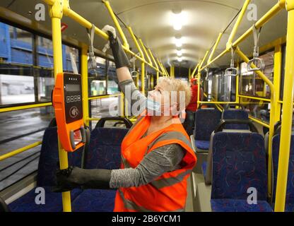 Ein Arbeiter, der eine Schutzmaske trägt, desinfiziert einen Personenkraftwagenbus als präventive Maßnahme gegen das COVID-19-Coronavirus in einem Trolleybusdepot.Vom 12. März bis 3. April 2020 führt die Ukraine eine dreiwöchige Quarantäne ein, um dem neuen Coronavirus COVID-19 wegen der weltweiten "ovid-19-Coronavirus-Epidemie" entgegenzuwirken. Die Quarantäne in der Ukraine sieht die Schließung von Bildungseinrichtungen, das Verbot von Massenversammlungen von mehr als 200 Personen, die Schließung von Luftdiensten mit einigen Ländern vor. Die Weltgesundheitsorganisation erklärte das Coronavirus am 11. März 2020 zu einer globalen Pandemie. Stockfoto