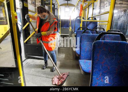 Ein Arbeiter, der eine Schutzmaske trägt, desinfiziert einen Personenkraftwagenbus als präventive Maßnahme gegen das COVID-19-Coronavirus in einem Trolleybusdepot.Vom 12. März bis 3. April 2020 führt die Ukraine eine dreiwöchige Quarantäne ein, um dem neuen Coronavirus COVID-19 wegen der weltweiten "ovid-19-Coronavirus-Epidemie" entgegenzuwirken. Die Quarantäne in der Ukraine sieht die Schließung von Bildungseinrichtungen, das Verbot von Massenversammlungen von mehr als 200 Personen, die Schließung von Luftdiensten mit einigen Ländern vor. Die Weltgesundheitsorganisation erklärte das Coronavirus am 11. März 2020 zu einer globalen Pandemie. Stockfoto