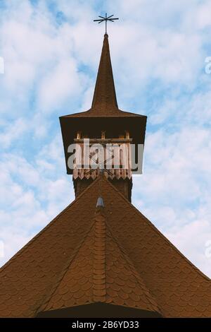 Blick nach oben auf den Kirchturm einer alten Holzkirche an einem bewölkten Himmel in Maramures Stockfoto