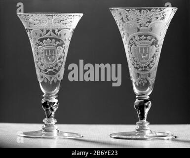 Kelkglas traf auf het wapen van de familiie Van Beuningen Chalice Glas aus klarem, farblosem Glas. Flacher Fuß. Der verdrehte Balusterstamm hat eine rote Spirale, eine Luftblase und drei Mereses. Der trompetenförmige Kelch hat einen abgerundeten Boden. Auf dem Kelch befindet sich in einer Kartusche, bestehend aus Voluten mit mattierten Flächen mit Punkten und Kreisen, umgeben von Arbeitsblatt, ein Oval mit den bekrönten Familienarmen Van Beuningen, das von zwei Armen flankiert wird, die unten aneinander gebunden sind. Entlang des Mundrandes ein Reifen mit symmetrischen Blatt- und Blumenarbeitszweigen und zwei Tauben zwischen einem gezähnten Rand und einem Str. Stockfoto