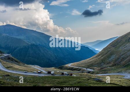 Autos, die durch die kurvenreiche Bergstraße fahren, mit nebligen, waldbedeckten Bergen im Hintergrund Stockfoto