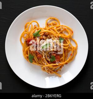 Köstliche Hausgemachte Bucatini alle Amatriciana Pasta in einem weißen Teller auf schwarzem Hintergrund, Blick über den Kopf. Flaches Lay, von oben, Draufsicht. Nahaufnahme. Stockfoto