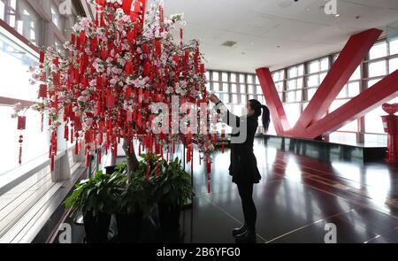 Shanghai. März 2020. Eine Touristin hängt ihre Wunschkarte auf der Aussichtsplattform des Jin Mao Tower im Osten Chinas Shanghai, 12. März 2020. Der Shanghai Tower, Chinas höchstes Gebäude, hat seine Touristenattraktion "Top of Shanghai Observatory" am Donnerstag wieder eröffnet. Zwei weitere Sehenswürdigkeiten begannen ab Donnerstag auch Touristen zu empfangen, darunter der Shanghai Oriental Pearl Tower und der Shanghai Jinmao Tower. Um MIT 'Shanghai Skyscraper Sceneries, Landmarks to Reopen' zu GEHEN Credit: Fang Zhe/Xinhua/Alamy Live News Stockfoto