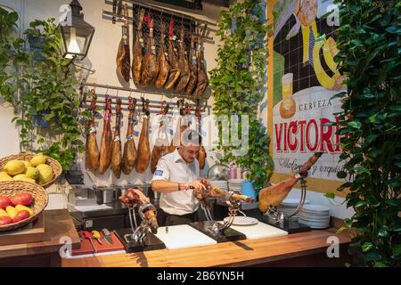 Innenbereich Bodego-Bar El Pimpi. Ein Kortador oder Schinkenschneider, der ein Bein aus Schinken zerschnitt. Málaga, Costa del Sol, Provinz Málaga, Andalusien, Südspanien. Stockfoto