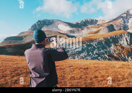 Touristen fotografieren Berge, die mit Wolken bedeckt sind, auf einem Smartphone. Ein Reisender nimmt Fotos und Videos von erstaunlicher Natur auf digitalen Medien auf. Adv Stockfoto