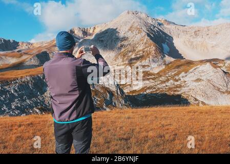 Touristen fotografieren Berge, die mit Wolken bedeckt sind, auf einem Smartphone. Ein Reisender nimmt Fotos und Videos von erstaunlicher Natur auf digitalen Medien auf. Adv Stockfoto