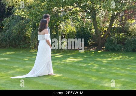 Schöne schwangere junge Frau, die an einem schönen Sommertag Hand in Hand mit ihrem Partner geht Stockfoto