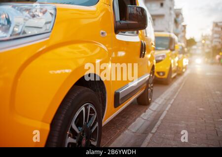 Gelbes Taxi auf dem Parkplatz, das auf den Kunden wartet. Taxi auf der Straße. Eine Reihe von Taxis auf dem Bürgersteig, die von Scheinwerfern angezündet werden Stockfoto
