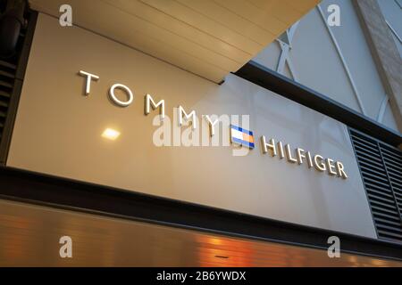 Name Baord und Logo von Tommy Hilfiger über der Ladenfront im Gunwharf Quays Einkaufszentrum, Portsmouth, Hampshire, Südküste Englands Stockfoto