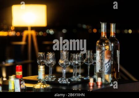 Nachtszenen mit verschiedenen Flaschen und Brillen aus Alkohol und Spirituosen an einer Bar. Große Auswahl an importierten und inländischen Etiketten. Stockfoto