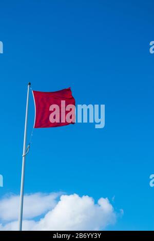 Rote Warnmarkierung fliegend in Steifer Brise Gegen blauen Himmel Stockfoto