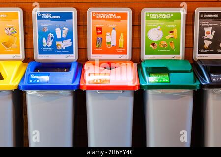 Ein komplettes Sortiment an Recycling-Entsorgungsbehältern in einer Gemeinschaftshalle Stockfoto