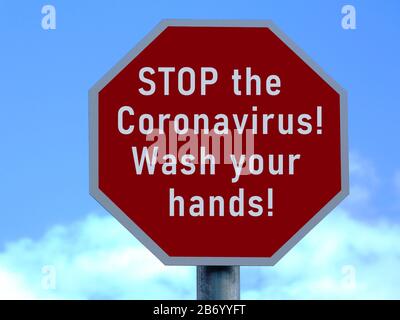 Stoppschild und Aufkleber zur Vermeidung von COVID-19. Waschen Sie sich Ihre Hände zur Erinnerung. Infektionskrankheit. Warnkonzept für Virusgefahr. Coronavirus. Blauer Himmel mit Wolken Stockfoto