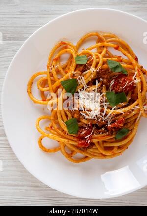 Hausgemachte Bucatini alle Amatriciana Pasta auf einem Teller auf einem weißen Holztisch, Draufsicht. Flaches Lay, oben, von oben. Nahaufnahme. Stockfoto