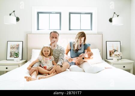 Gerade auf Porträt einer vierköpfigen Familie sitzen zusammen auf einem Bett Stockfoto