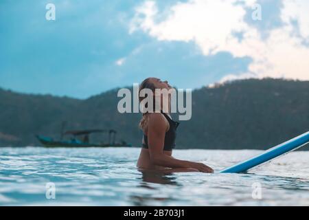 Surferin im Meer bei Sonnenuntergang Stockfoto