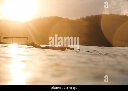 Surferin im Meer bei Sonnenuntergang Stockfoto