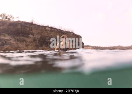 Gerne Frau sitzt auf Surfbrett im Meer Stockfoto