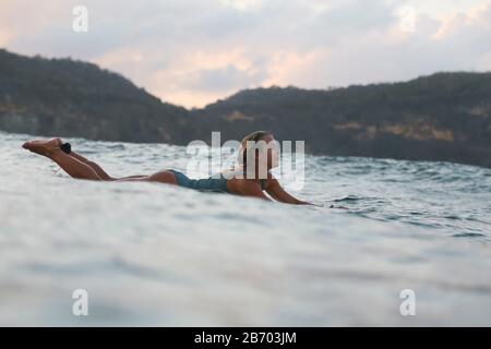 Surferin im Meer bei Sonnenuntergang Stockfoto