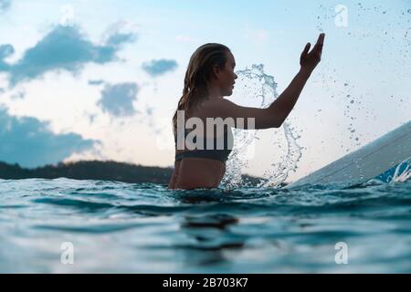 Surferin im Meer bei Sonnenuntergang Stockfoto