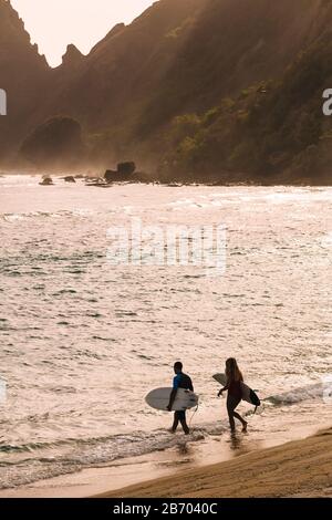 Ein Paar läuft am Strand mit dem Surfbrett Stockfoto