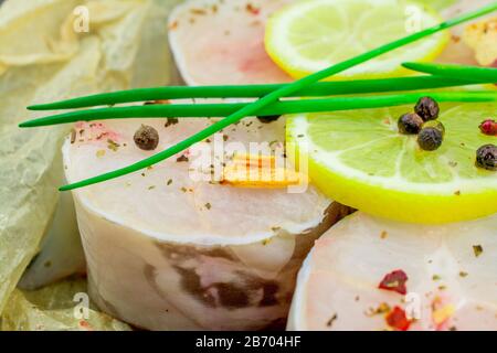 Frische Fischfilets aus Kongeraal, Zitronenkräuter, Pfeffer, Salz auf schwarzem Grund Stockfoto