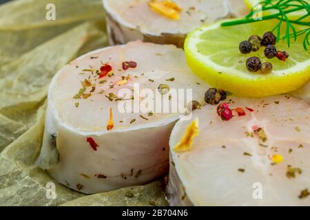 Frische Fischfilets aus Kongeraal, Zitronenkräuter, Pfeffer, Salz auf schwarzem Grund Stockfoto