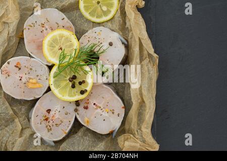 Frische Fischfilets aus Kongeraal, Zitronenkräuter, Pfeffer, Salz auf schwarzem Grund Stockfoto